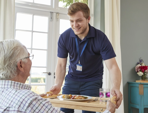 Male Care Worker Serving Dinner To A Senior Man At 2024 10 19 02 13 05 Utc